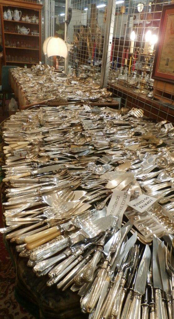 Fragment stanowiska 51 na Warszawslich Targach Antyków - stół pełen starych osrebrzanych sztućców
