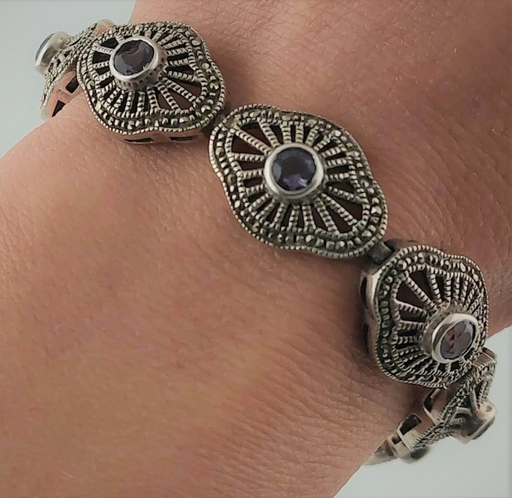 srebrna ażurowa bransoletka z markazytami i fioletowymi kamieniami na ręce