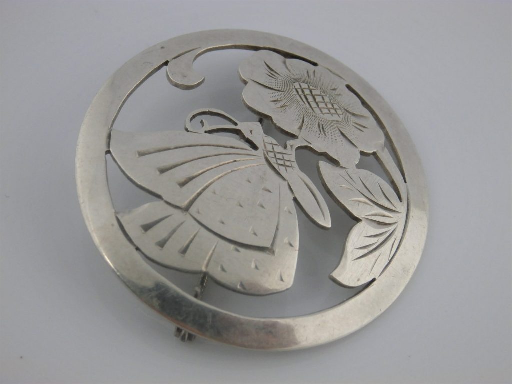 ażurowa ręcznie wycinana srebrna broszka z motywem motyla na kwiatach