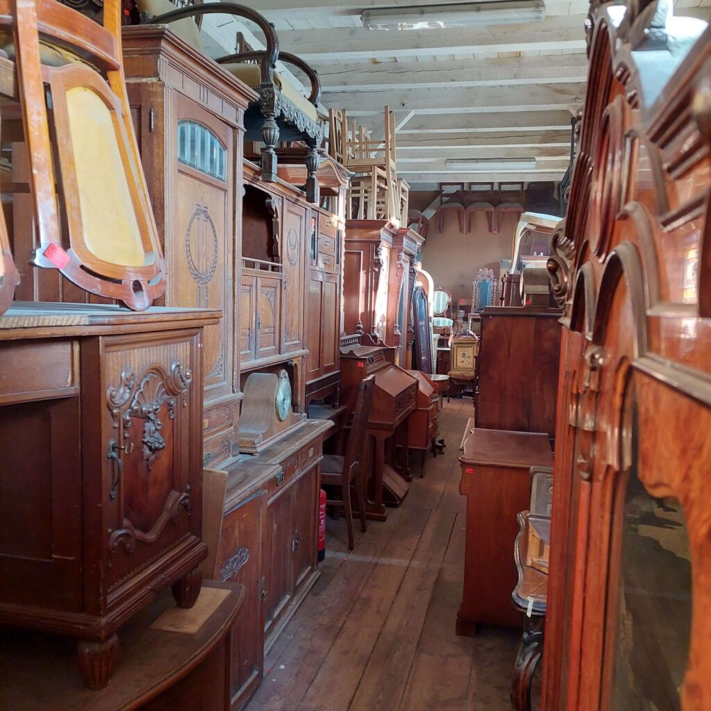 Antyczne meble w Magazynie Wystawowym Dessa Antyki Olsztyn: biurko, krzesło, kredens dębowy, fotel